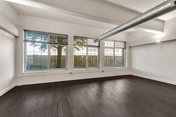 Empty loft space with dark wood floors and large windows at The Lofts at Elk Terminal Apartments, Buffalo, NY 14204