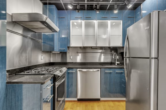a kitchen with stainless steel appliances and blue and white cabinets at The Lofts at Elk Terminal, New York