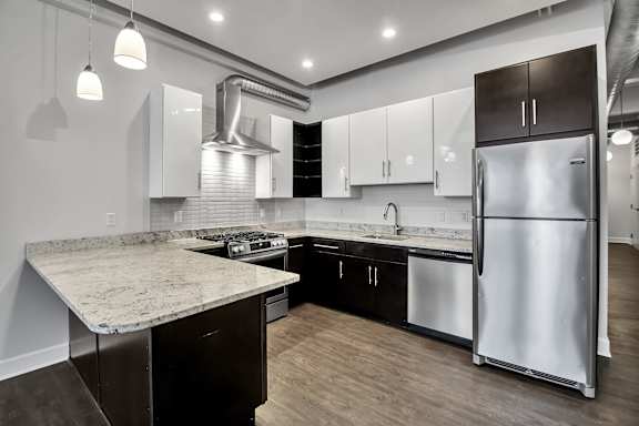 Modern kitchen with twotone cabinets and granite peninsula at The Lofts at Elk Terminal Apartments, Buffalo, 14204