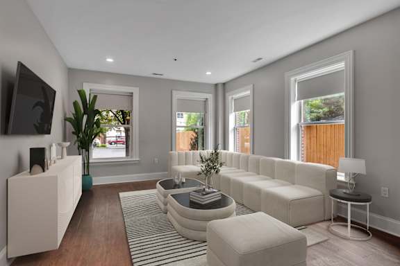 A modern living room with a white sofa set and a flat screen TV.