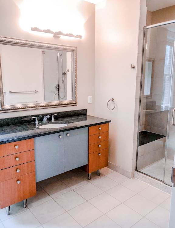 A bathroom with a sink, mirror, and shower at The Granite Works Apartments , Buffalo, NY