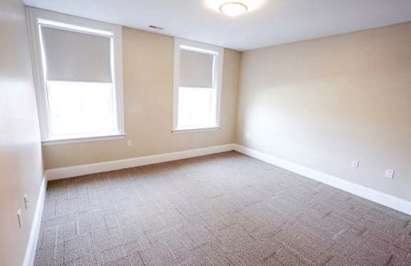 A room with a carpeted floor and two windows at The Granite Works Apartments , Buffalo, NY, 14202