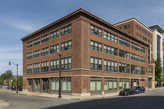 Historic brick corner building with large storefront windows at 100 South Apartments, Buffalo, NY