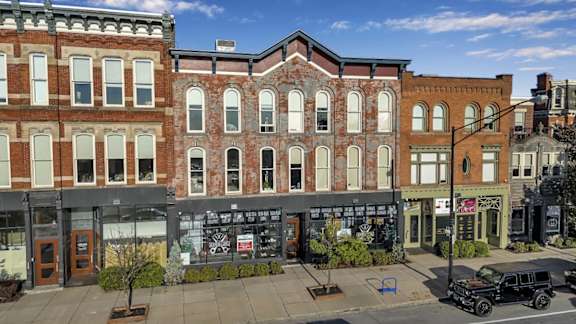A street view of a row of buildings with a black car parked on the sidewalk.