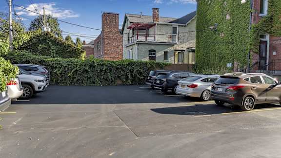 A parking lot with cars parked in front of a building with a green hedge.