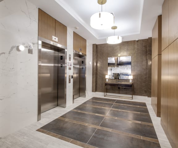a lobby with stainless steel refrigerators and elevators and marble floors at Nineteen North, New York, 14202