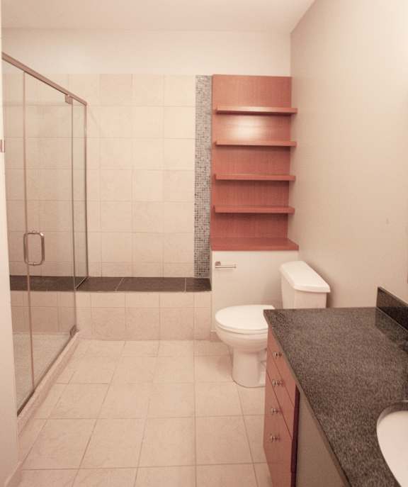 A bathroom with a walk in shower, toilet and a sink at The Granite Works Apartments , Buffalo, NY