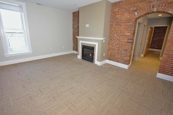 A room with a fireplace and brick wall at The Granite Works Apartments , Buffalo