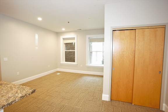 A room with a brown carpet and a wooden door at The Granite Works Apartments , Buffalo