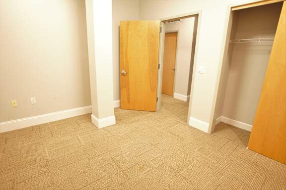 A room with a carpeted floor and two closed doors at The Granite Works Apartments , Buffalo, 14202