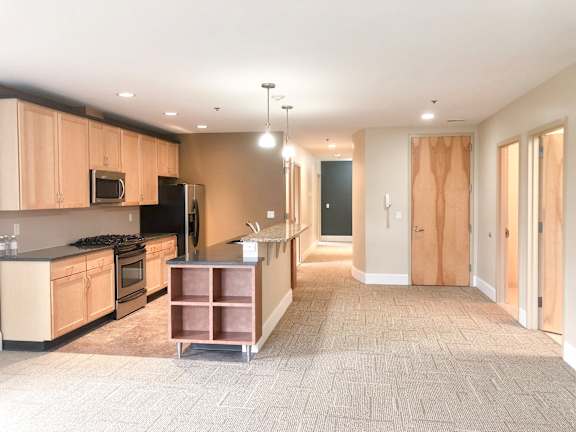 Floor Plan  A kitchen with a black refrigerator and stove top oven at The Granite Works Apartments , New York 14202