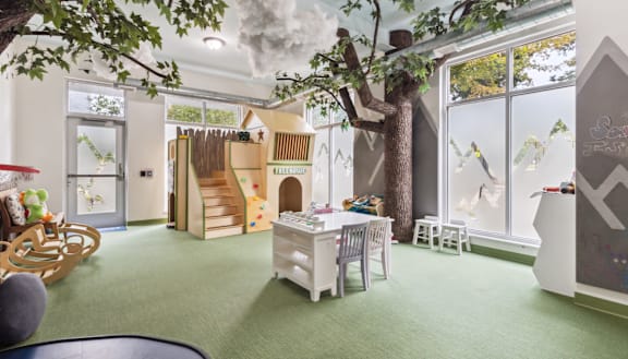 a playroom with a tree in the center of a room with a playhouse at Bakery Living in Pittsburgh, PA 15206