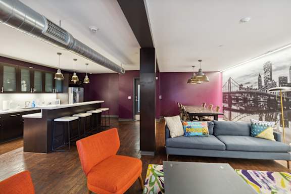 A living room with a couch, chair, and a kitchen area.at Walnut on Highland, Pennsylvania 15206