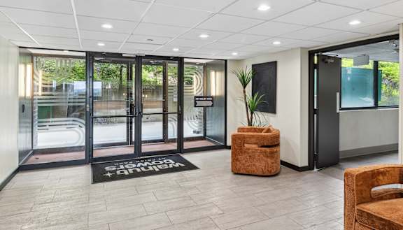 a lobby with doors and chairs and a rug in front of a pool at Walnut Towers at Walnut Towers at Frick Park, Pittsburgh