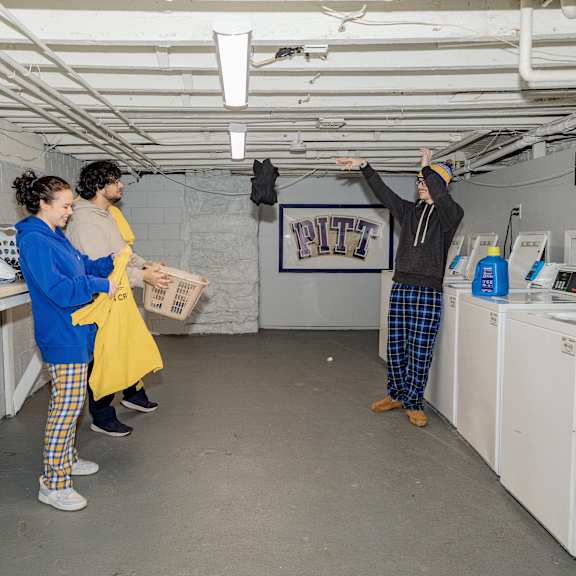 a man in a yellow raincoat points at something on the ceiling while two people look on at University Commons Apartments, Oakland, Pittsburgh