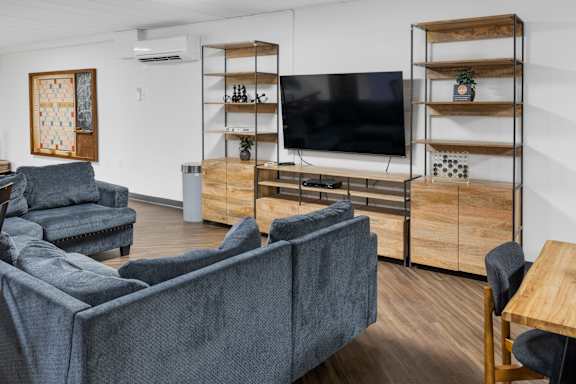 A living room with a grey couch, a television, and a wooden shelf. at Walnut Crossings, Monroeville, PA, 15146