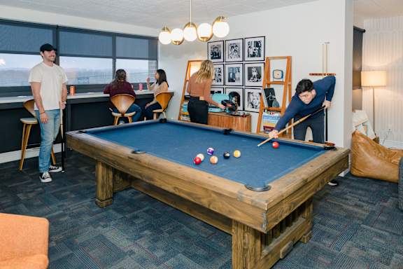 A group of people playing pool in a room at Walnut Towers at Frick Park, Pennsylvania