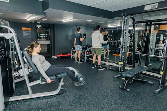 A woman is working out on a leg press machine in a gym at Walnut Towers at Frick Park, Pittsburgh, 15217