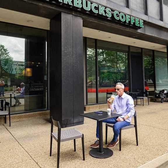 A man is sitting at a Starbucks table enjoying a beverage.  at The Commonwealth Building, Pittsburgh, 15222