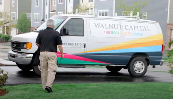 a man walking past a walnut capital van parked in a driveway at Highland Village, Pittsburgh, PA
