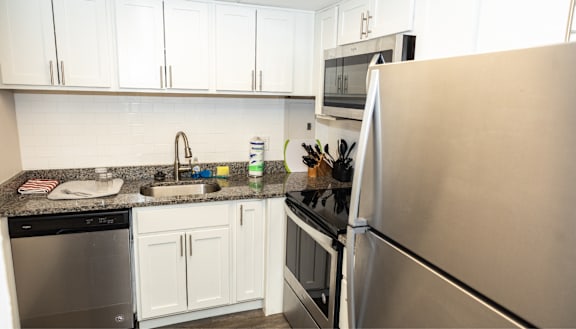 A kitchen with white cabinets and a stainless steel refrigerator.  at Walnut Crossings, Monroeville, PA, 15146