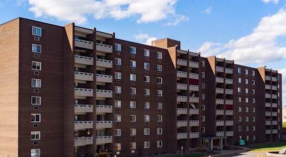 a large apartment building with many balconies and a parking lot in front of it at Walnut Crossings in Monroeville, PA 15146