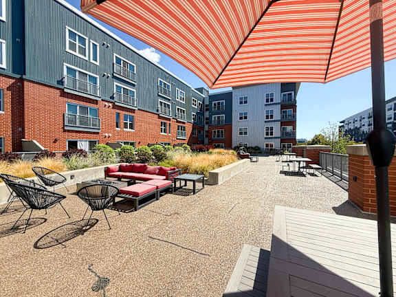 A patio with a red couch and chairs under a striped orange and white awning. Hot Metal Flats apartments, Southside Pittsburgh, PA