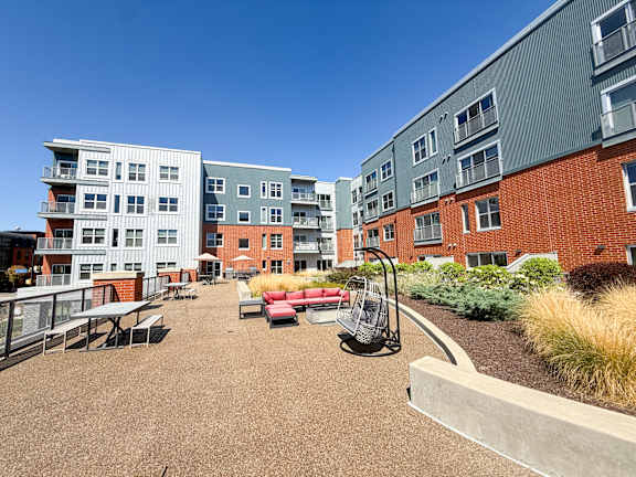 A playground area with a swing set and picnic tables in front of apartment buildings. Hot Metal Flats apartments, Southside Pittsburgh, PA