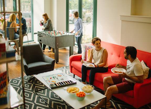 a group of people sitting in a living room with a foosball table in the background at Walnut on Highland, Pittsburgh, PA