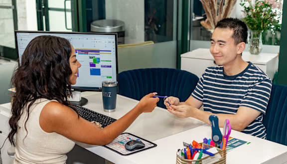 a man and a woman sitting at a desk in front of a computer