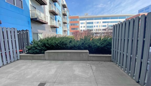 a large concrete planter with bushes and shrubs in front of an apartment building