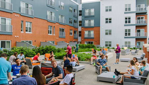 a group of people sitting and standing on a patio in front of an apartment building Hot Metal Flats apartments, Southside Pittsburgh, PA
