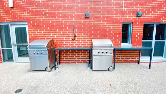 two stainless steel barbecue grills in front of a red brick wall Hot Metal Flats apartments, Southside Pittsburgh, PA