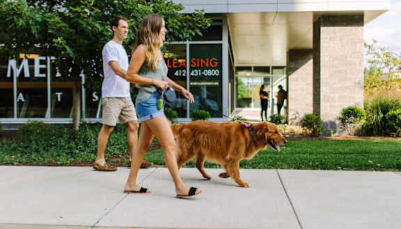 a man and a woman walking a dog on a leash on a sidewalk Hot Metal Flats apartments, Southside Pittsburgh, PA