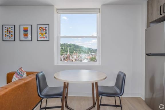 A dining room with a table and chairs and a window overlooking a cityscape.