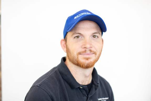 A man with a blue cap and a black shirt is looking at the camera.