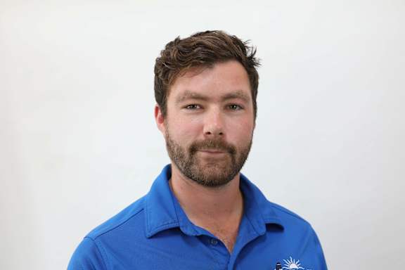 A man with a beard wearing a blue shirt with a logo on it.