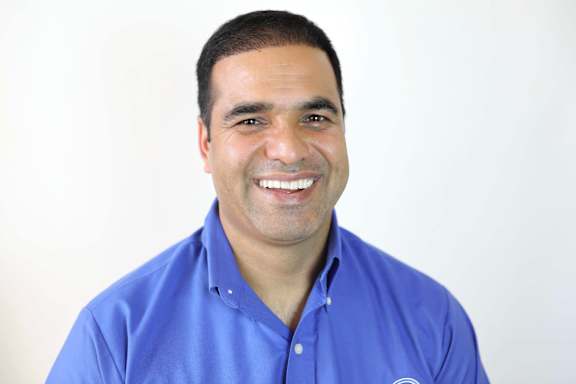 A man in a blue shirt is smiling.