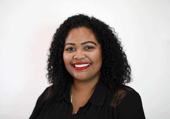 A woman with curly hair and a black shirt with lace details.