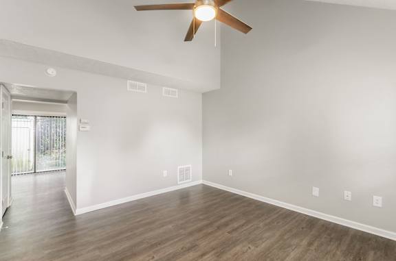 A room with a ceiling fan and wooden flooring.