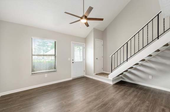 A spacious room with a staircase and a ceiling fan.