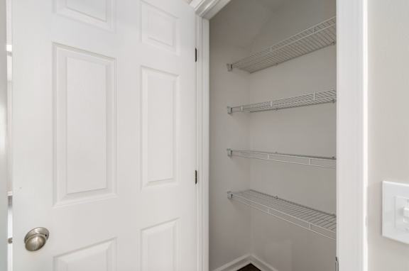 A white door is open to a white pantry with shelves.