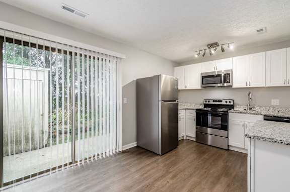 A kitchen with white cabinets and a stainless steel refrigerator.