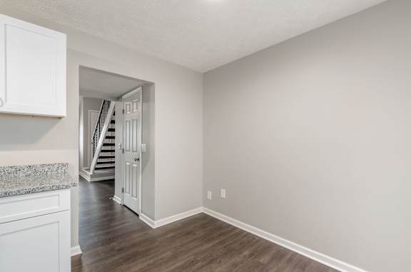 A room with a marble countertop and wooden flooring with a staircase in the background.