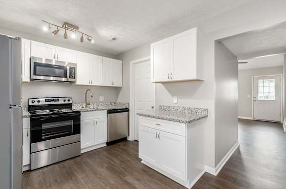 A kitchen with white cabinets and a granite countertop.