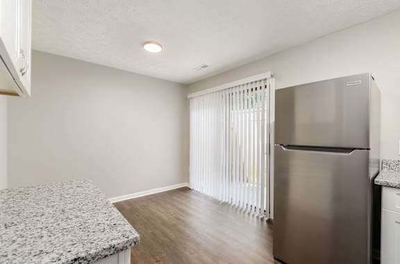 A kitchen with a granite countertop and a stainless steel refrigerator.