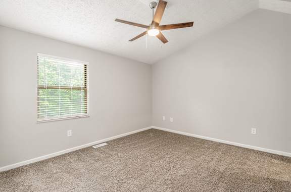 A room with a ceiling fan and a window with blinds.