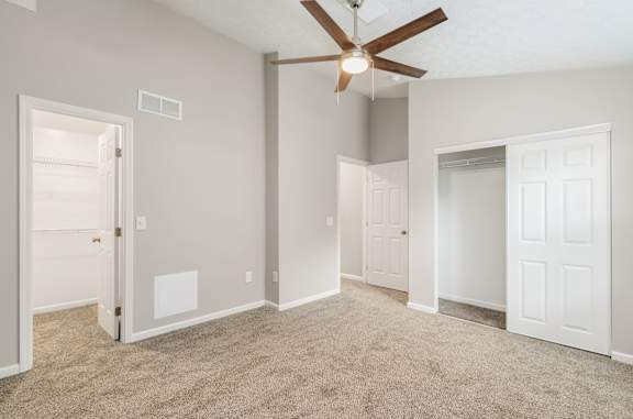 A room with a ceiling fan and carpeted floor.