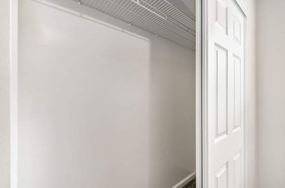 A white door is open to a white room.