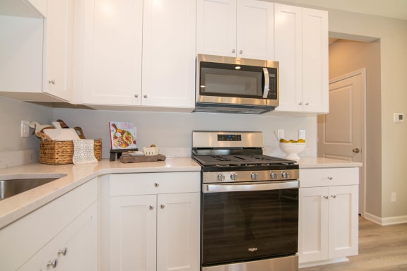 a kitchen with white cabinets and a stove and microwave at Jackson Run Townhomes, Whitestown, IN 46075